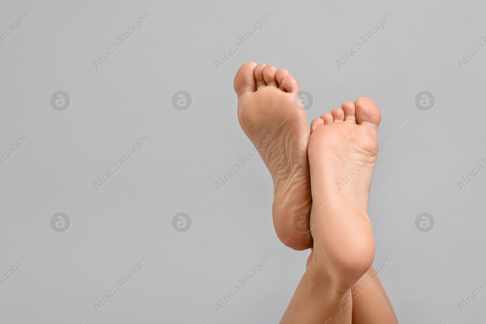 Woman with smooth feet on grey background, closeup. Space for text Photo of Woman with smooth feet on grey background, closeup. Space for text