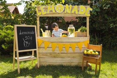 Photo of Cute little boy at lemonade stand in park