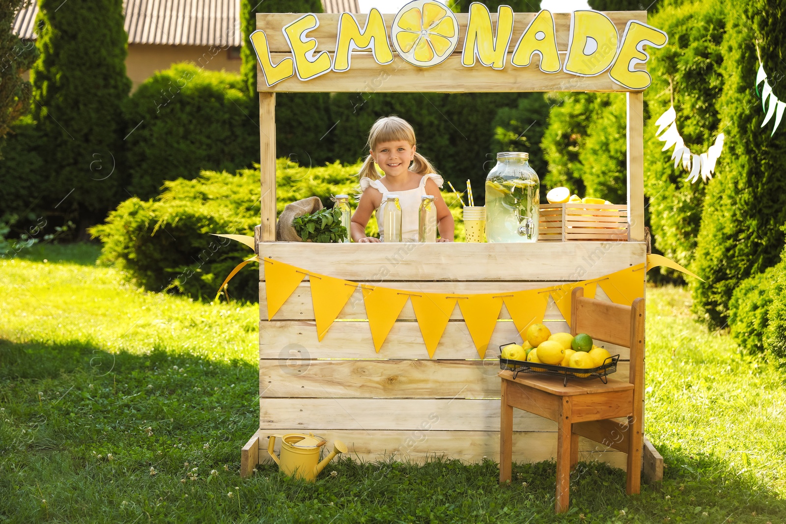 Photo of Cute little girl with refreshing drink at lemonade stand in park