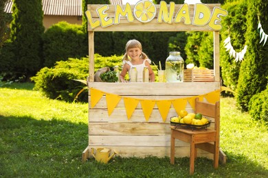 Cute little girl with refreshing drink at lemonade stand in park