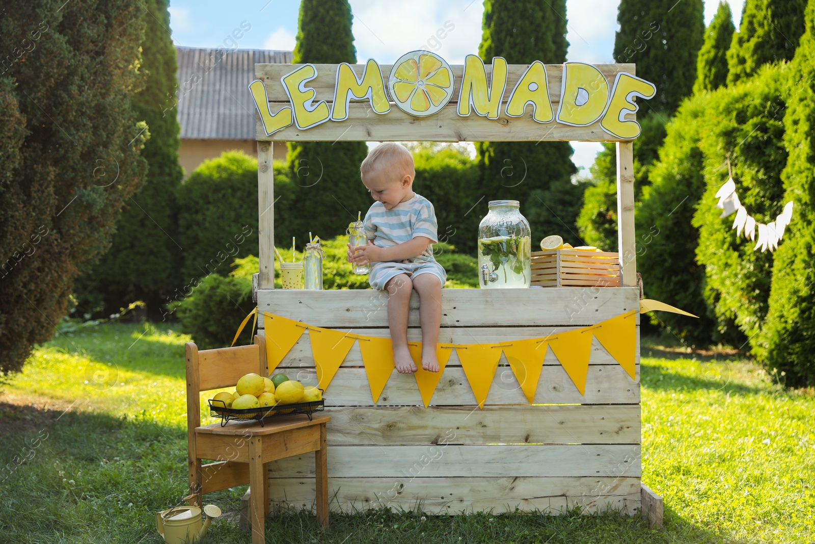 Photo of Cute little boy sitting on lemonade stand in park