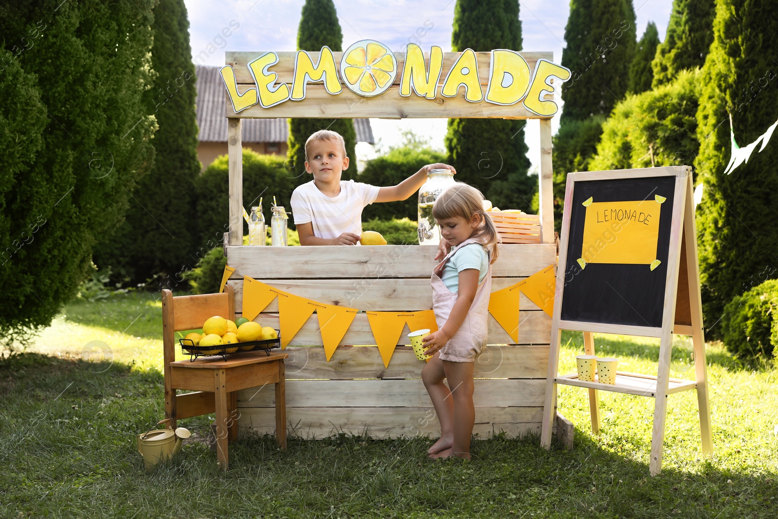 Photo of Cute little kids near lemonade stand in park