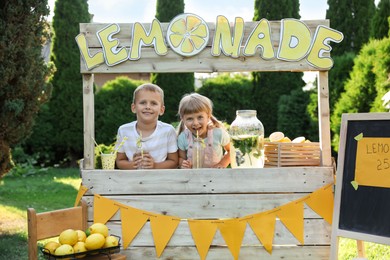 Cute little kids with refreshing drinks at lemonade stand in park