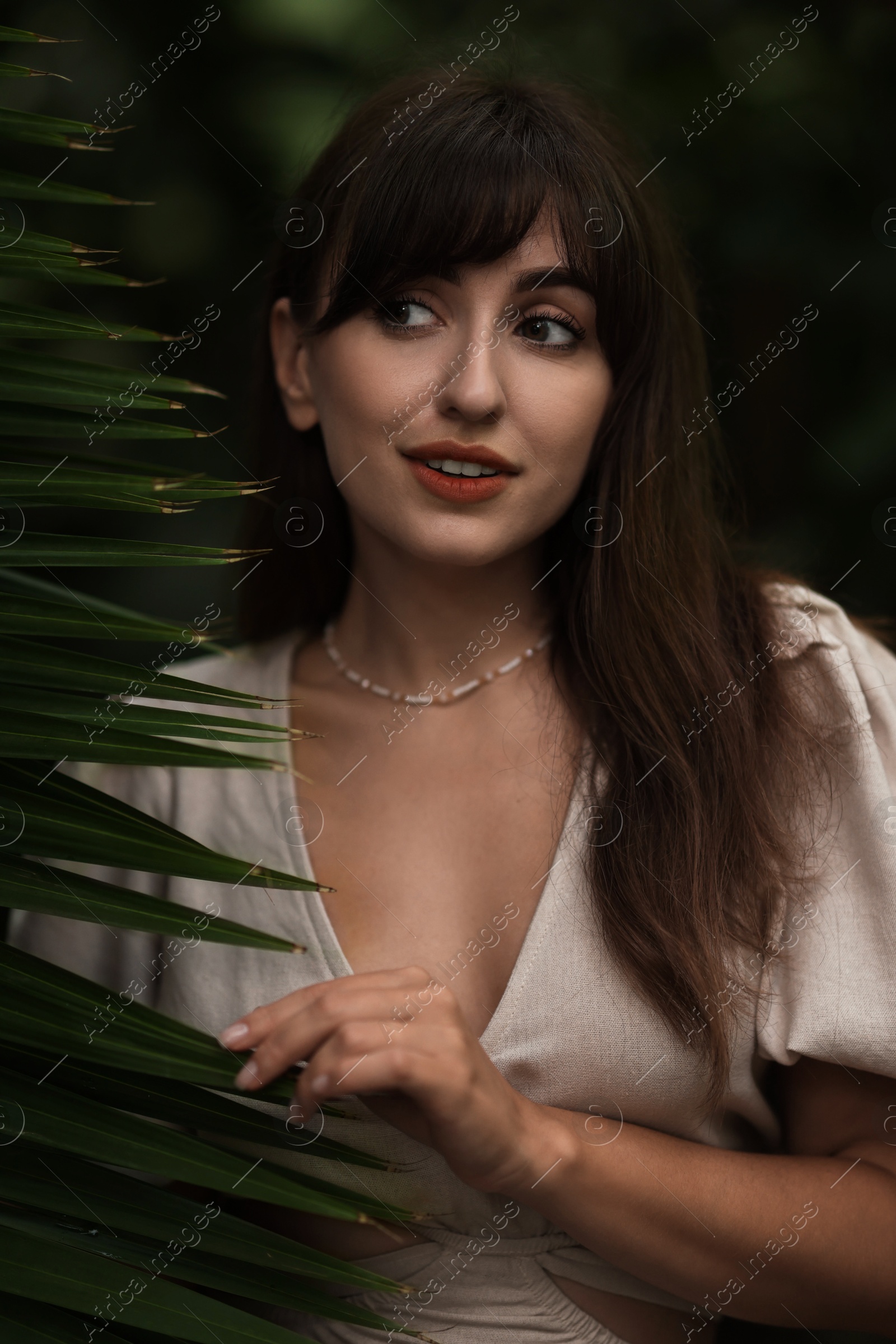 Photo of Portrait of beautiful woman with palm tree leaf outdoors