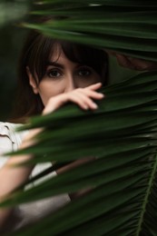 Portrait of beautiful woman with palm tree leaf outdoors