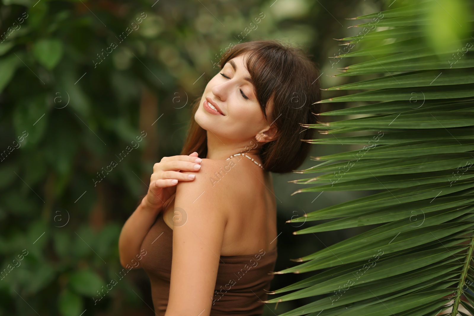 Photo of Portrait of smiling woman near palm leaves outdoors