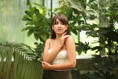 Photo of Beautiful woman posing near palm tree leaves