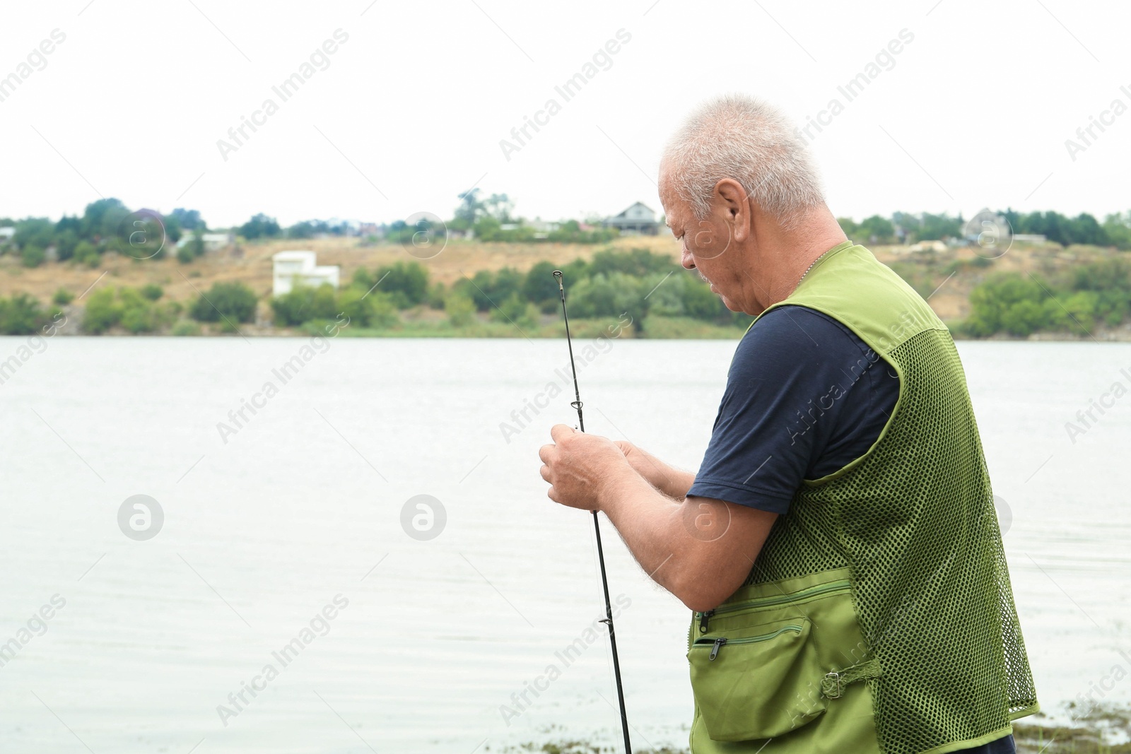 Photo of Fisherman with rod fishing near lake at summer