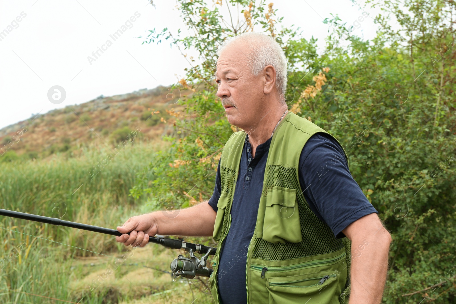 Photo of Fisherman with rod fishing near lake at summer