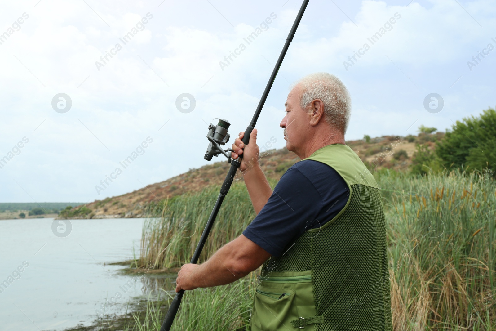 Photo of Fisherman with rod fishing near lake at summer