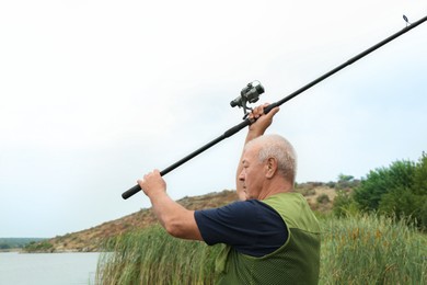 Photo of Fisherman with rod fishing near lake at summer