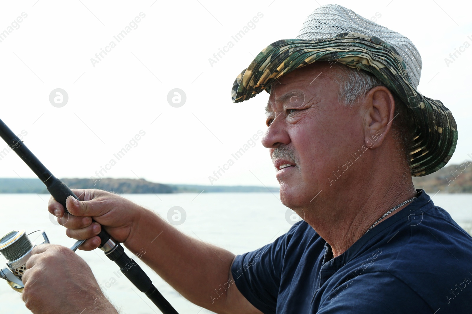 Photo of Fisherman with rod fishing near lake at summer