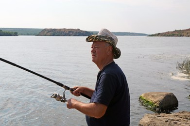 Photo of Fisherman with rod fishing near lake at summer