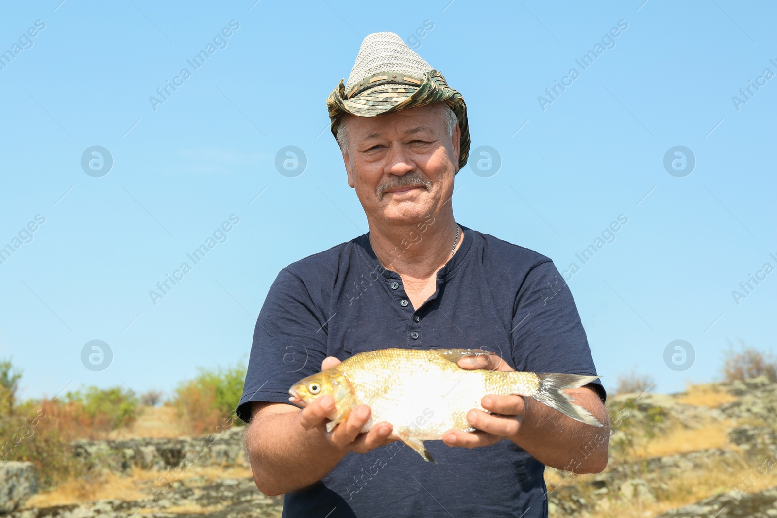 Photo of Fisherman holding caught fish outdoors at summer