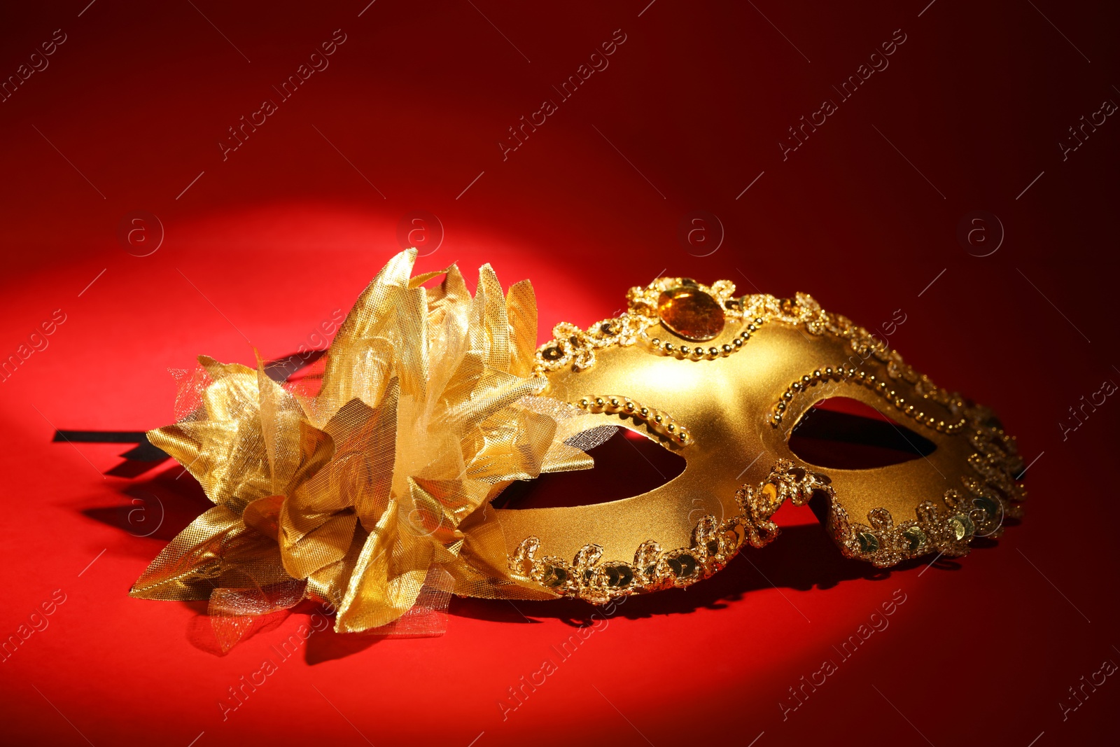 Photo of Beautiful golden carnival mask on red background