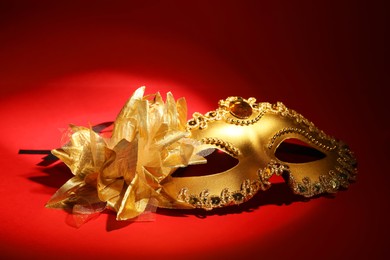 Photo of Beautiful golden carnival mask on red background