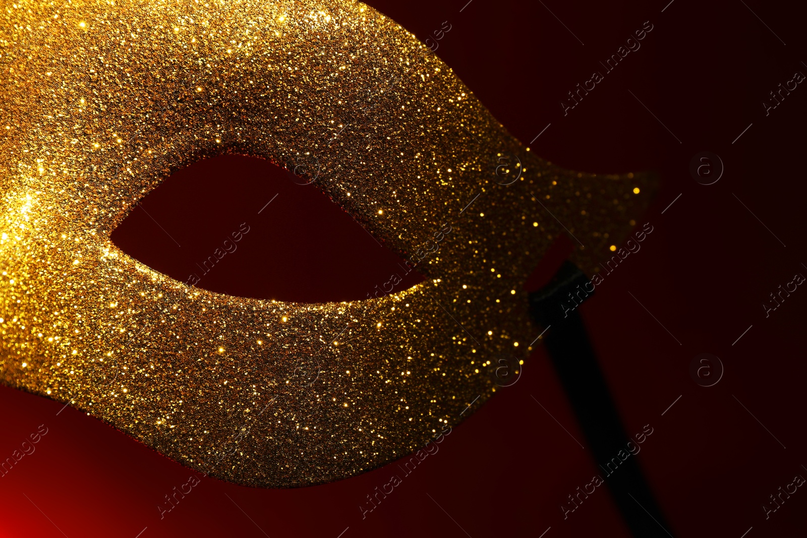 Photo of Beautiful golden carnival mask on red background, closeup