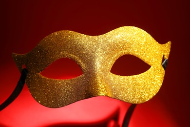 Photo of Beautiful golden carnival mask on red background