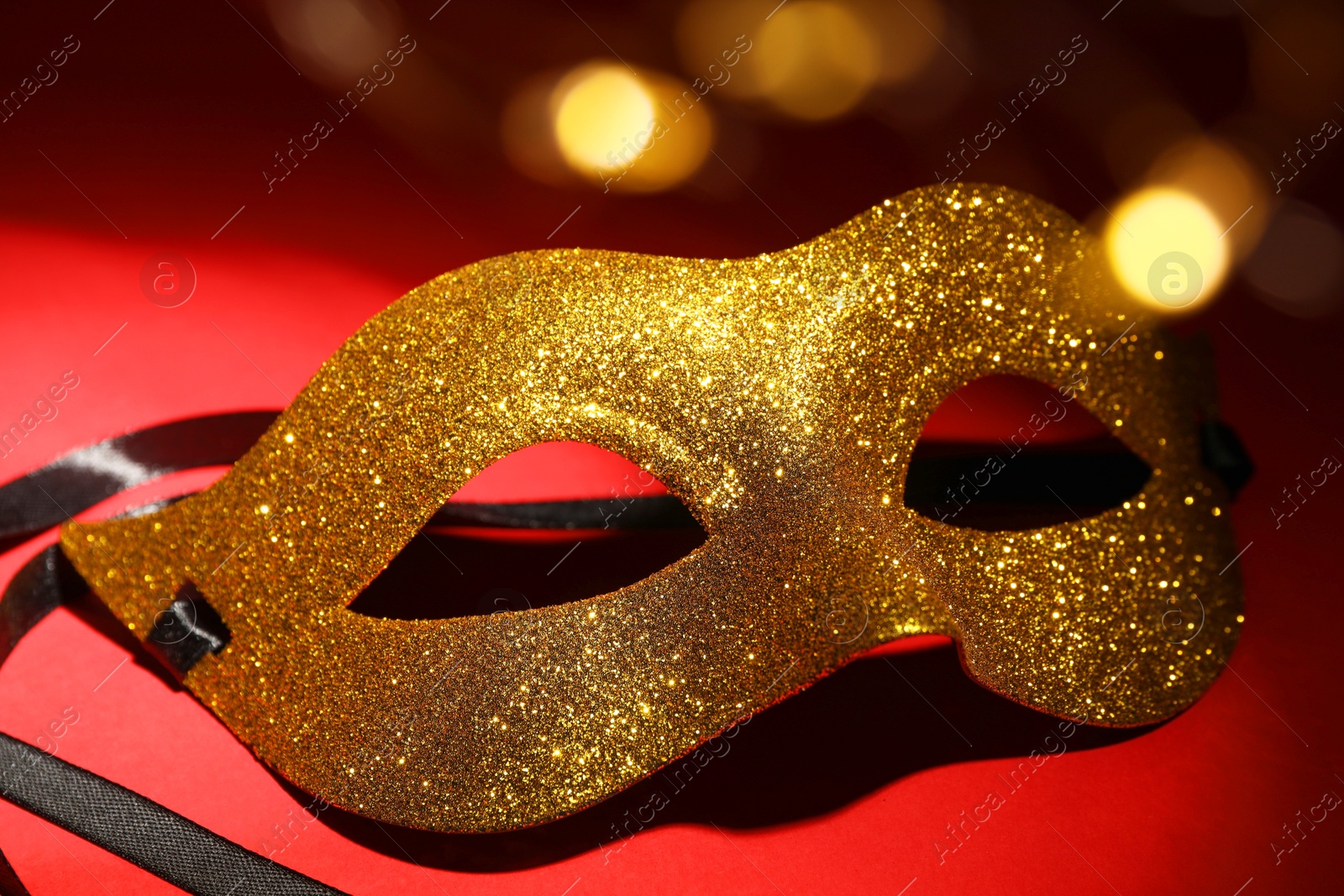 Photo of Beautiful golden carnival mask on red background, closeup