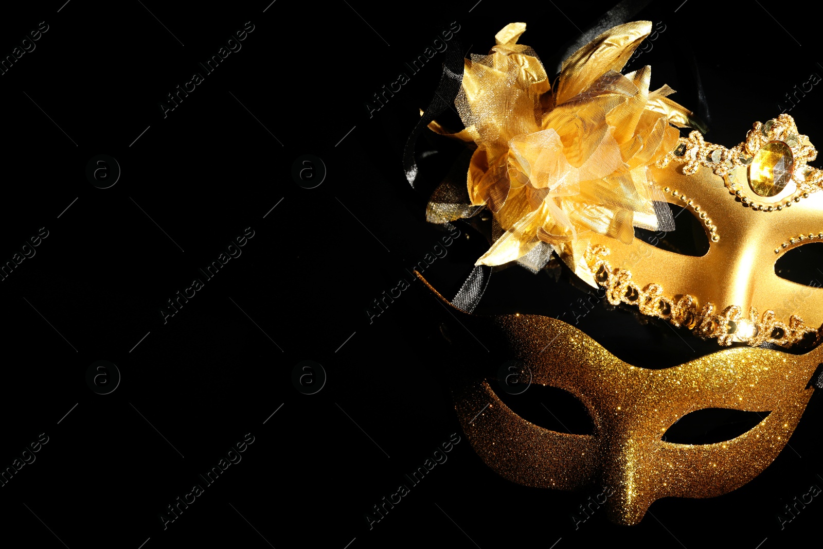 Photo of Beautiful golden carnival masks on black background, above view. Space for text