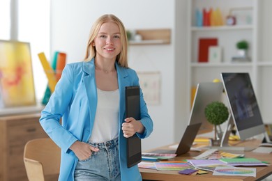 Beautiful young designer with tablet in office