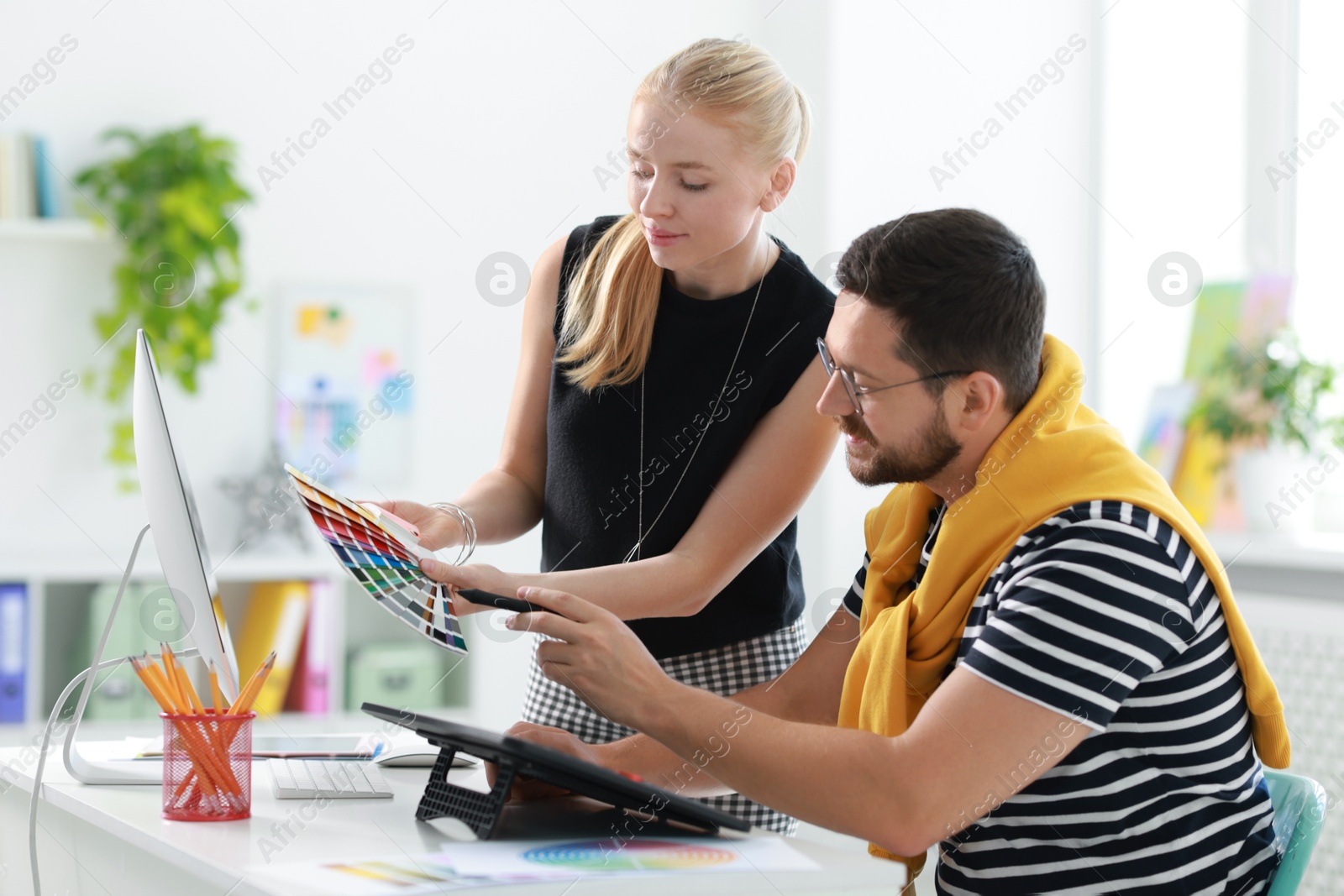 Photo of Designers with color samples and tablet working together in office