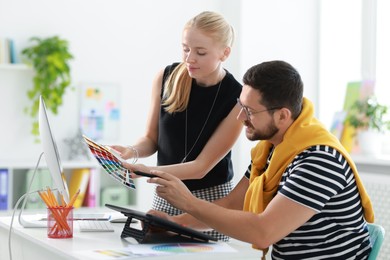 Designers with color samples and tablet working together in office