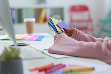 Designer with color samples working at table in office, closeup