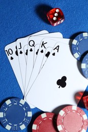 Photo of Playing cards, poker chips and cubes on blue table, flat lay