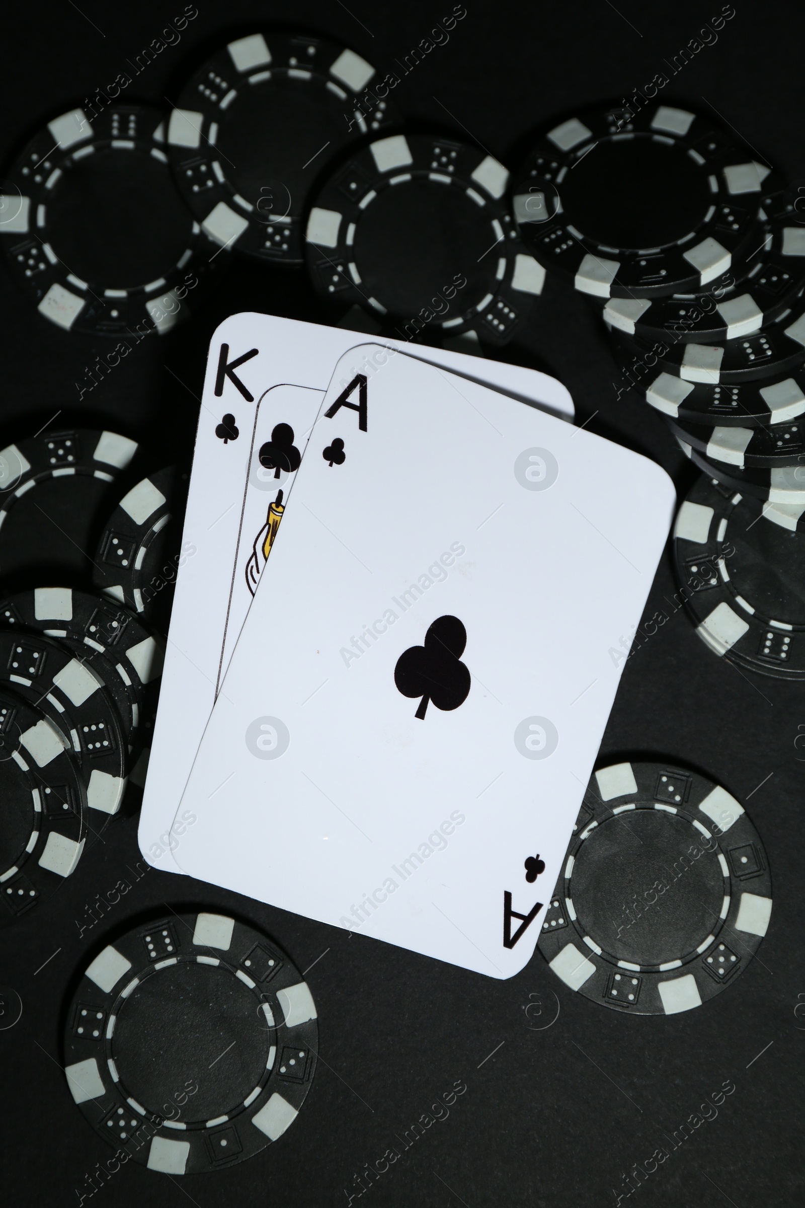 Photo of Playing cards and poker chips on black table, flat lay