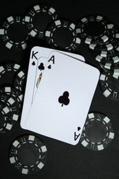 Playing cards and poker chips on black table, flat lay