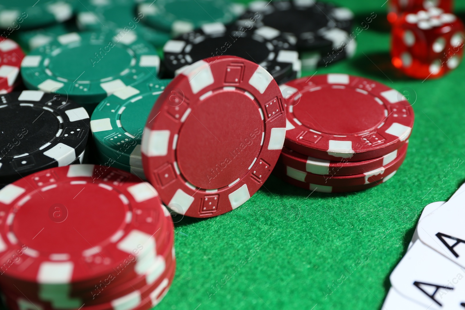 Photo of Poker chips and playing cards on green table, closeup