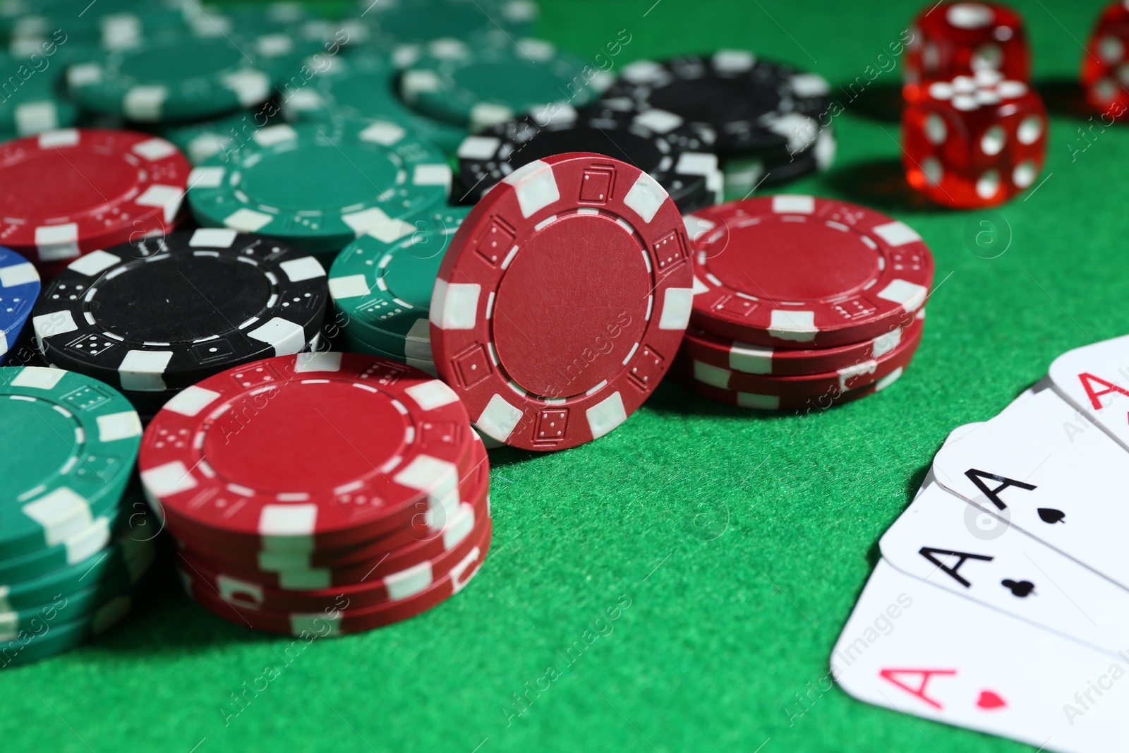 Photo of Poker chips and playing cards on green table, closeup