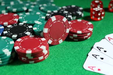 Poker chips and playing cards on green table, closeup