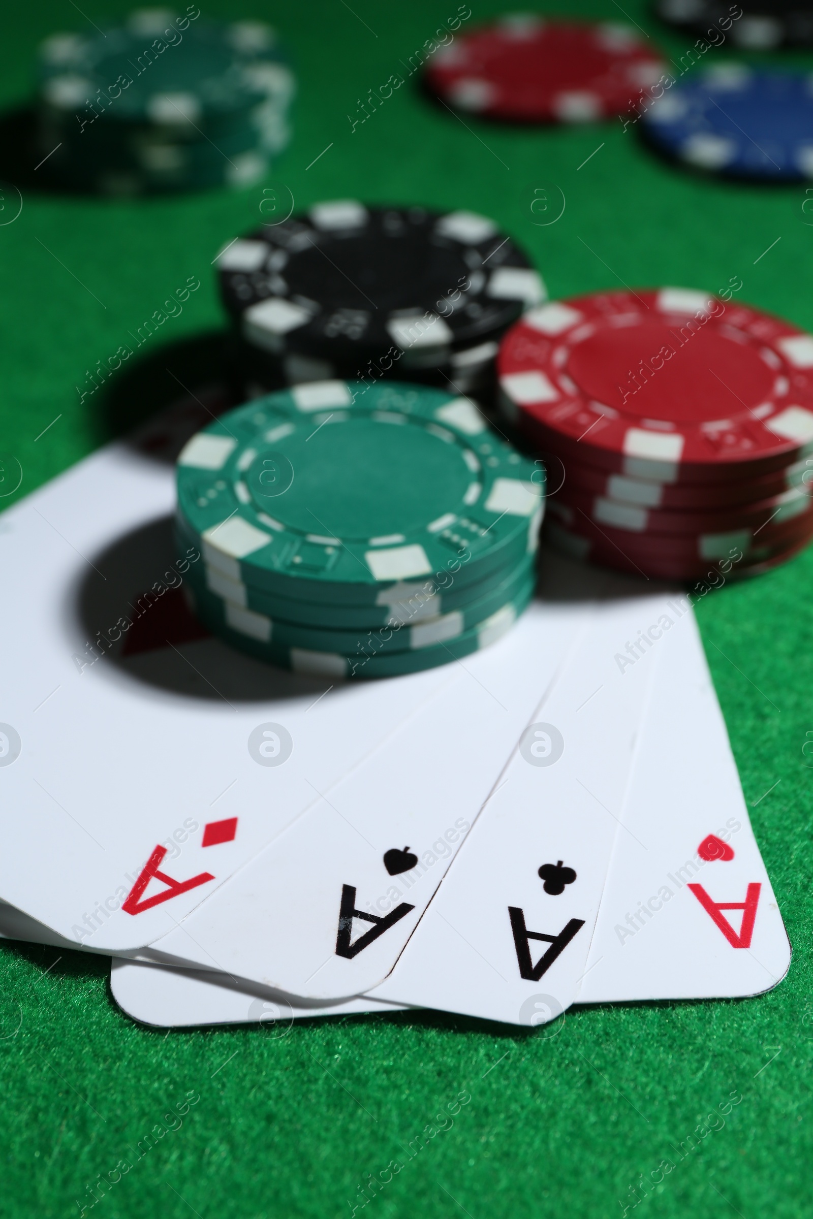 Photo of Playing cards and poker chips on green table, closeup