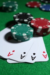 Playing cards and poker chips on green table, closeup