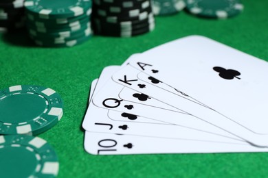 Photo of Playing cards and poker chips on green table, selective focus