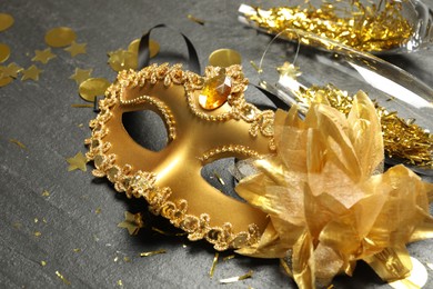 Photo of Beautiful golden carnival mask and glasses on gray textured table, closeup