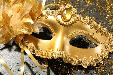 Photo of Beautiful golden carnival mask and confetti on gray textured table, top view