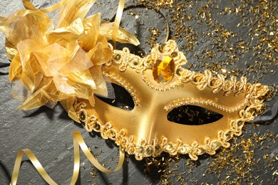 Beautiful golden carnival mask and confetti on gray textured table, top view