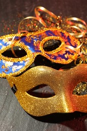 Photo of Beautiful carnival masks on gray textured table, closeup