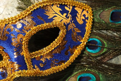 Beautiful bright carnival mask and peacock feathers on table, top view