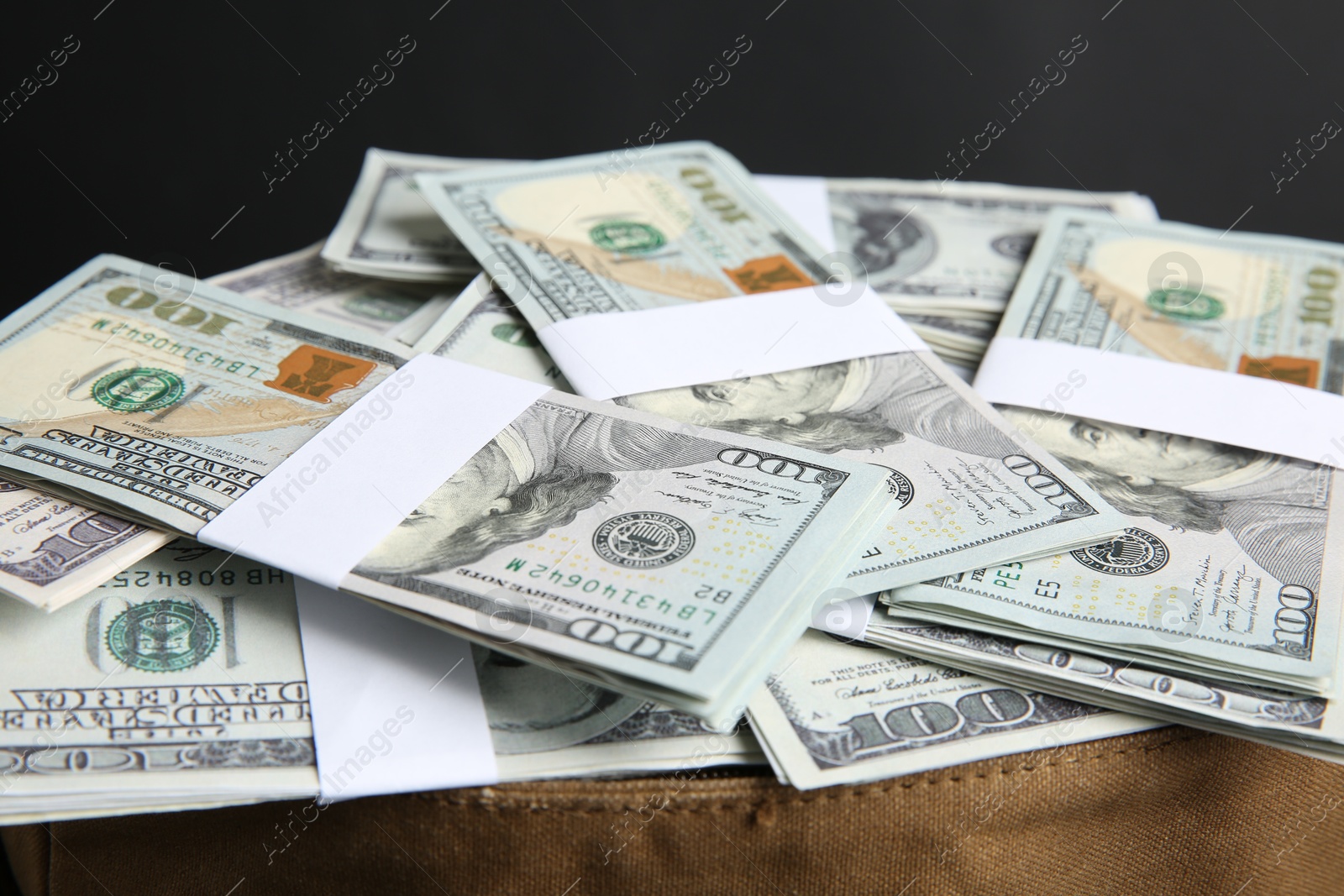 Photo of Dollar banknotes in bag on black background, closeup