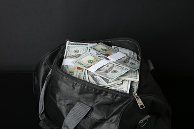 Photo of Dollar banknotes in bag on black table, closeup