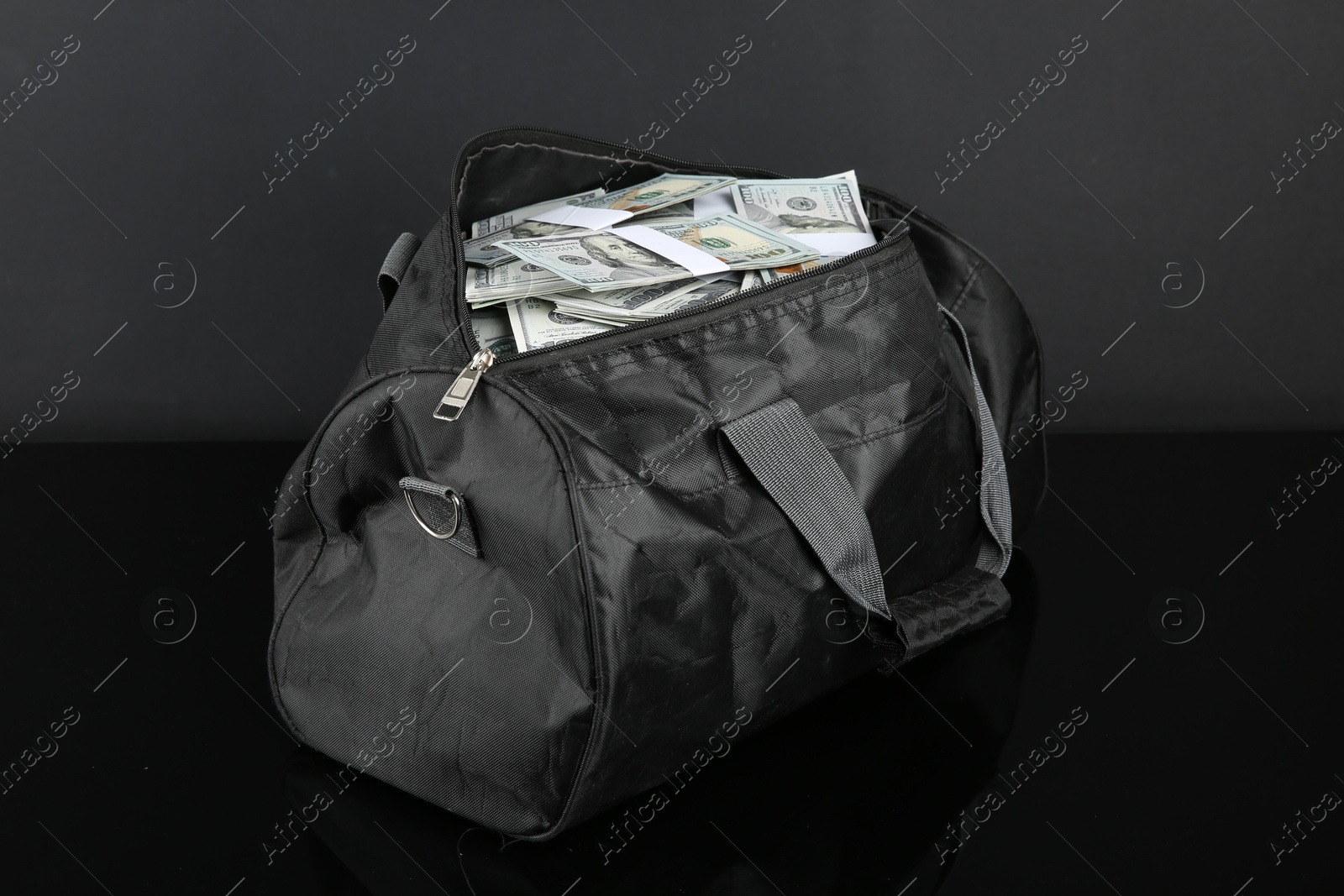 Photo of Dollar banknotes in bag on black mirror surface