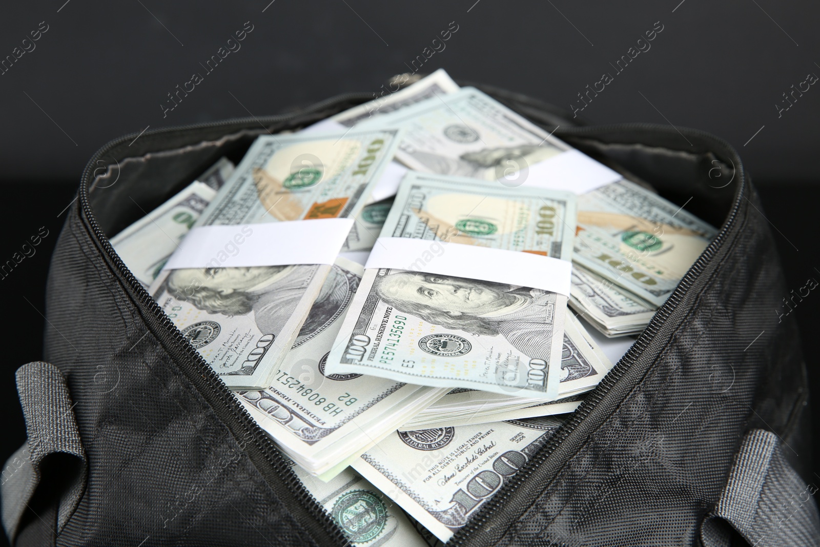 Photo of Dollar banknotes in bag on black background, closeup