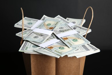 Photo of Dollar banknotes in paper bag on black background, closeup