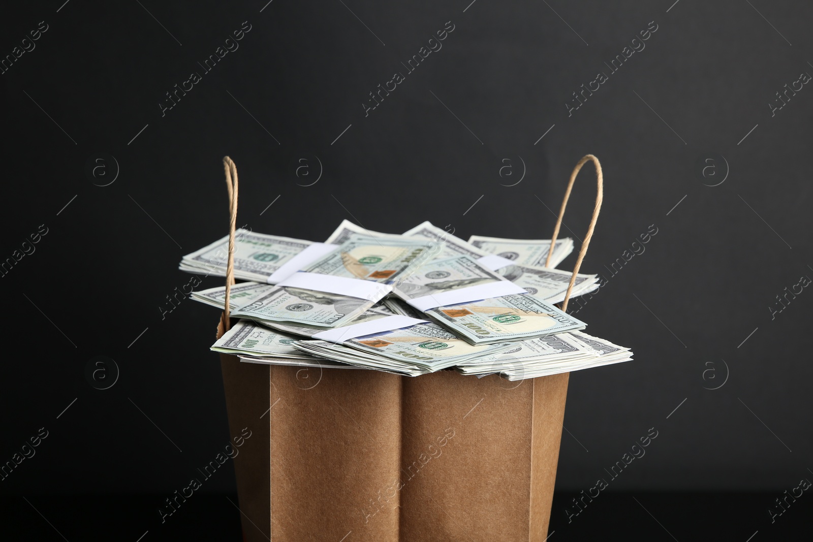 Photo of Dollar banknotes in paper bag on black background, closeup