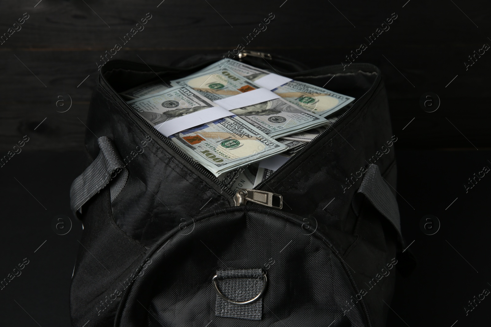 Photo of Dollar banknotes in bag on black table, closeup