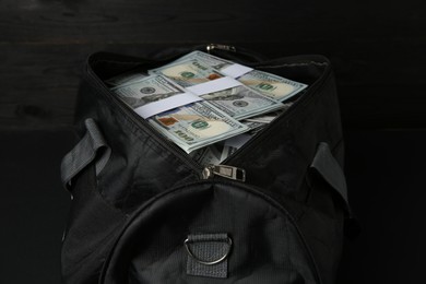 Photo of Dollar banknotes in bag on black table, closeup